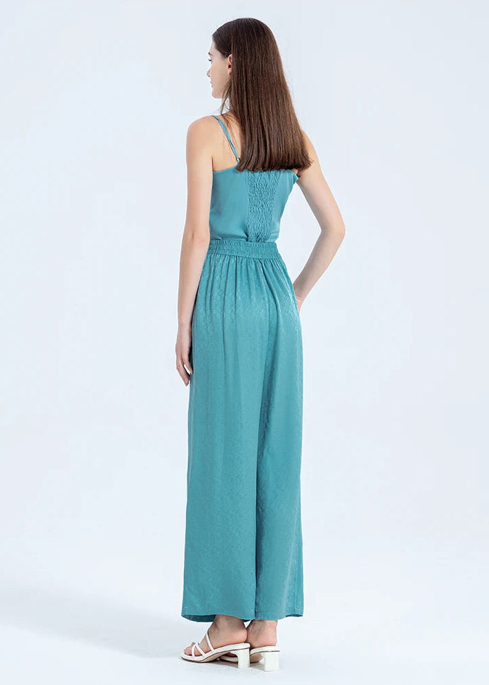 Full-height back view of a woman wearing Mulberry silk trousers, displaying the soft gathers from the elasticated back waistband. — From Borcelleclothes.