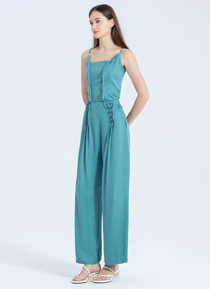Woman poses full-length with hands behind her back, highlighting the clean front finish and fluid silhouette of the Lapis Waters silk trousers. — From Borcelleclothes.