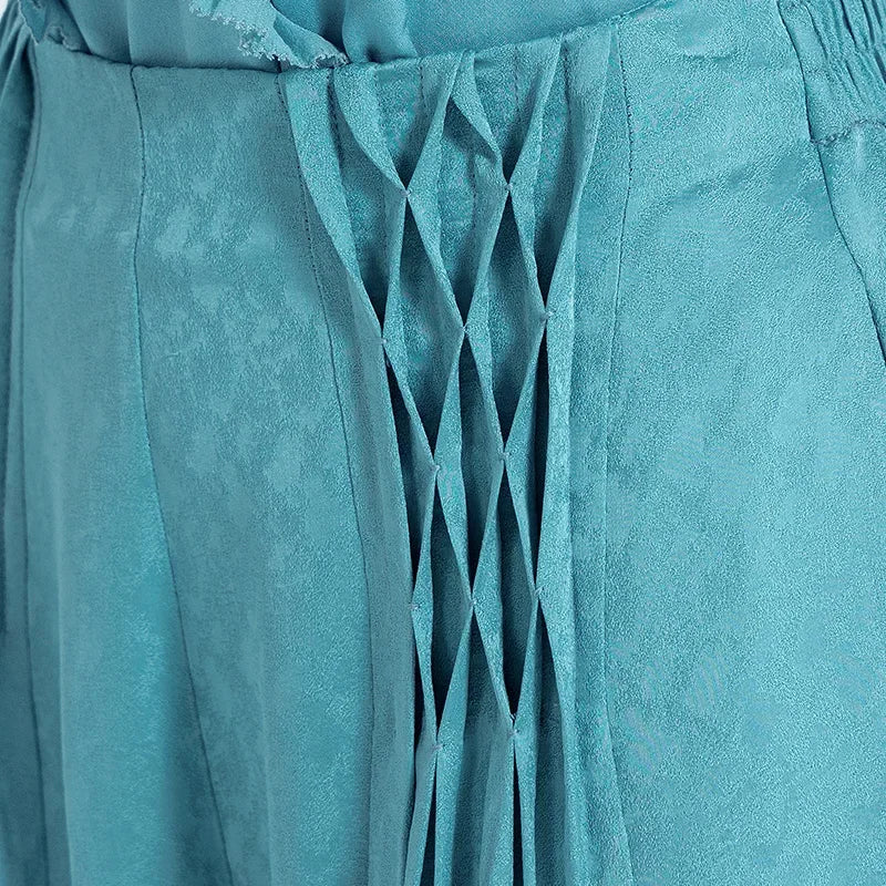 Close-up of the front waist section on a woman, revealing hand-stitched lattice pleats and the intricate jacquard weave of Lapis Waters silk. — From Borcelleclothes.
