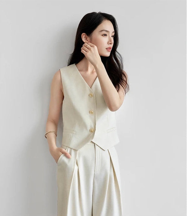 Woman adjusting her earring, highlighting the V-neckline of the linen blend vest. From Borcelleclothes.