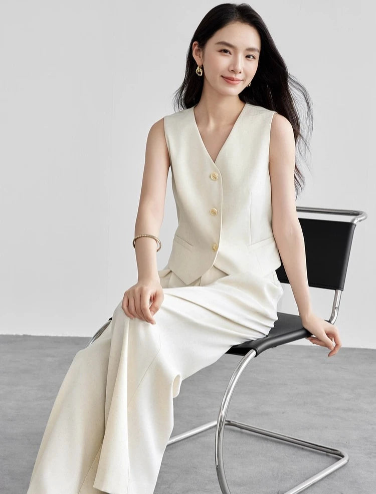 Seated woman with her hand on her knee, showing the drape of the linen blend trousers. From Borcelleclothes.