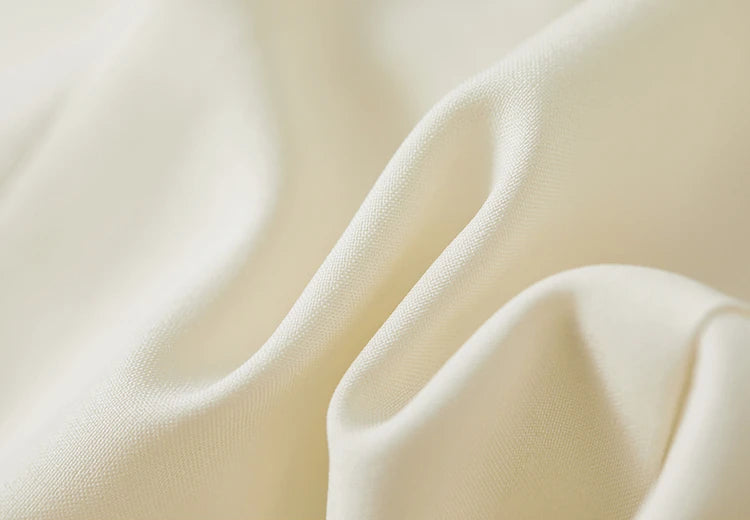 Detailed view of the cream linen blend fabric in a wave-like folded texture. From Borcelleclothes.