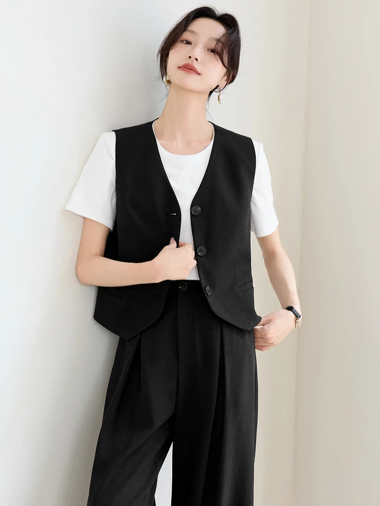 Woman holding the front edges of an unfastened dark linen blend vest. From Borcelleclothes.