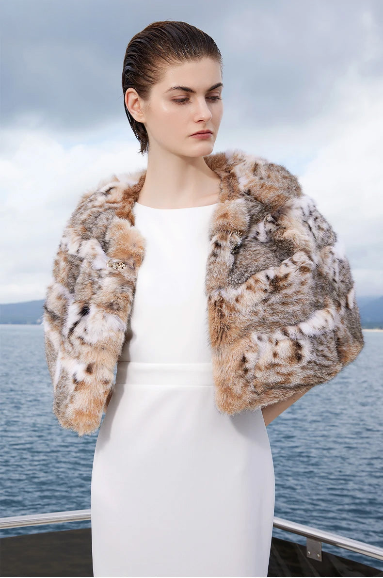 Model with hands behind her back wearing the lynx cape in Shades of Forest, highlighting the rounded silhouette from behind — From Borcelleclothes.