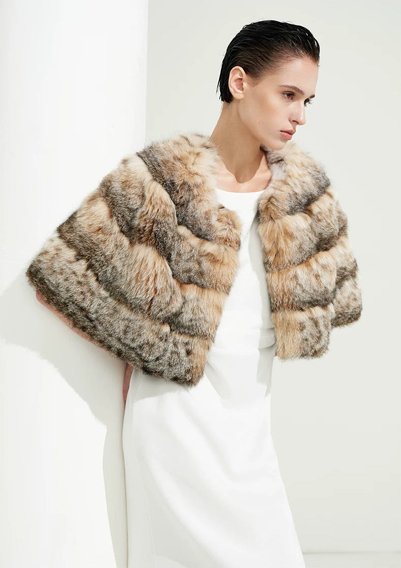 Woman leaning thoughtfully against an architectural column enveloped in certified natural bobcat fur — From Borcelleclothes.