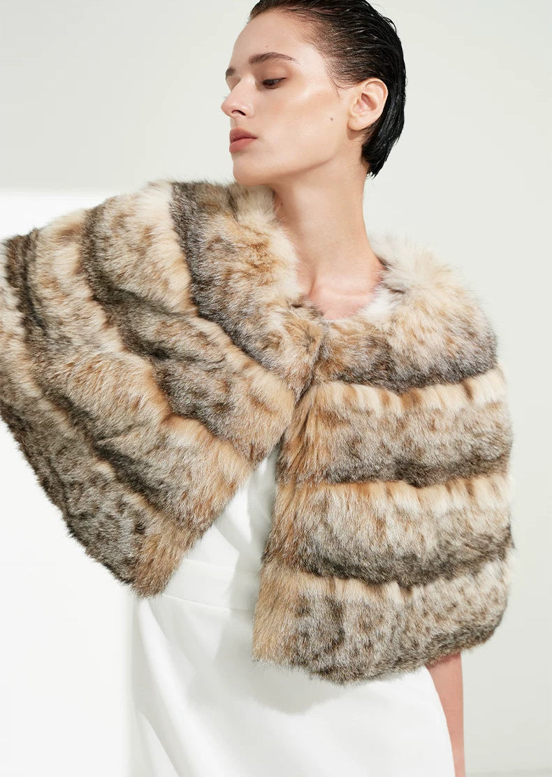 Woman raising her arm to reveal the fluid silhouette and meticulous horizontal pelt paneling of the lynx cape — From Borcelleclothes.