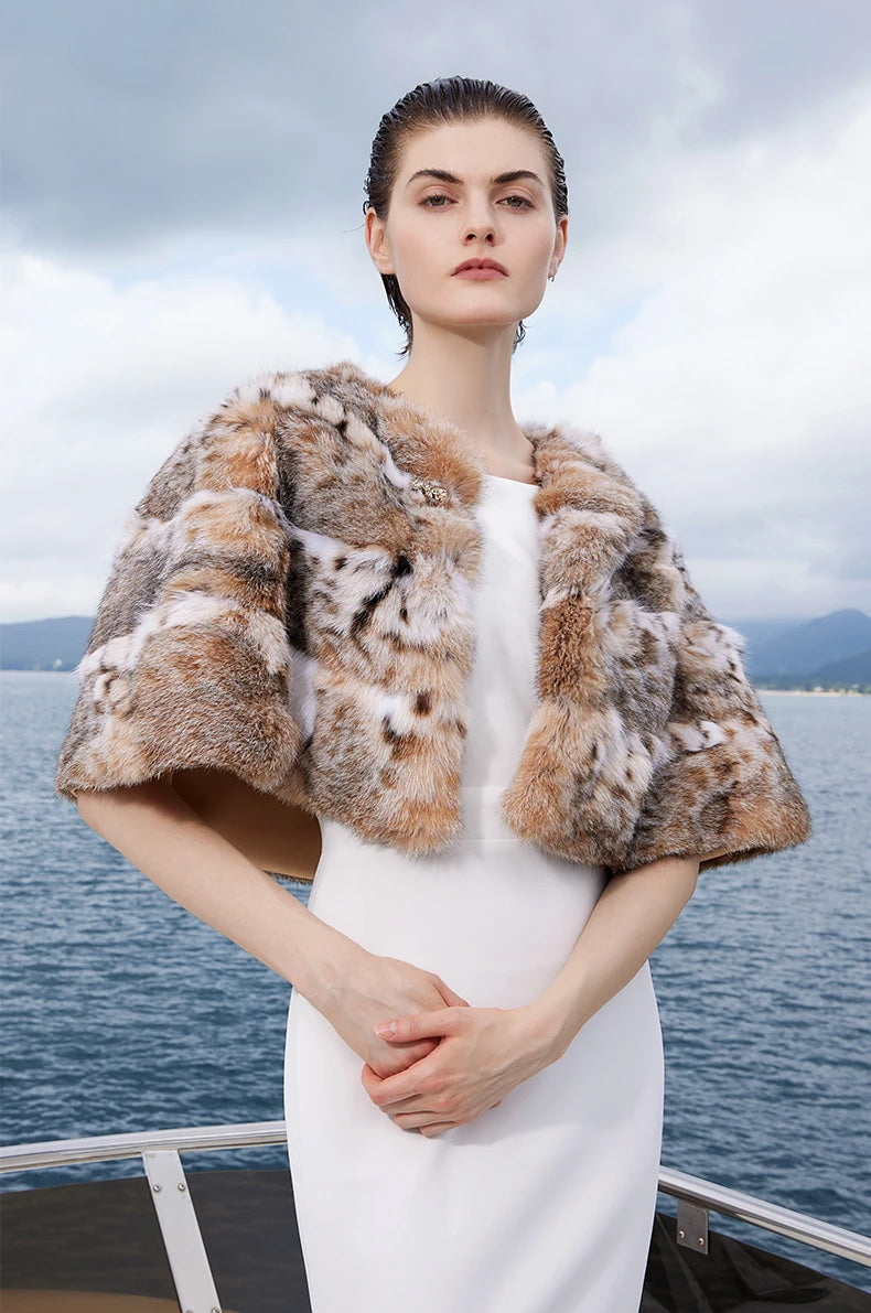 Model gently touching her fingers in the lynx fur cape in Shades of Forest, conveying softness and natural movement — From Borcelleclothes.