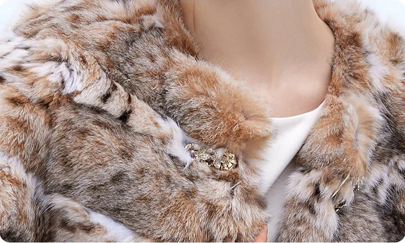 Close-up of the sculpted gold-tone clasp at the neckline of the lynx cape in Shades of Forest — From Borcelleclothes.