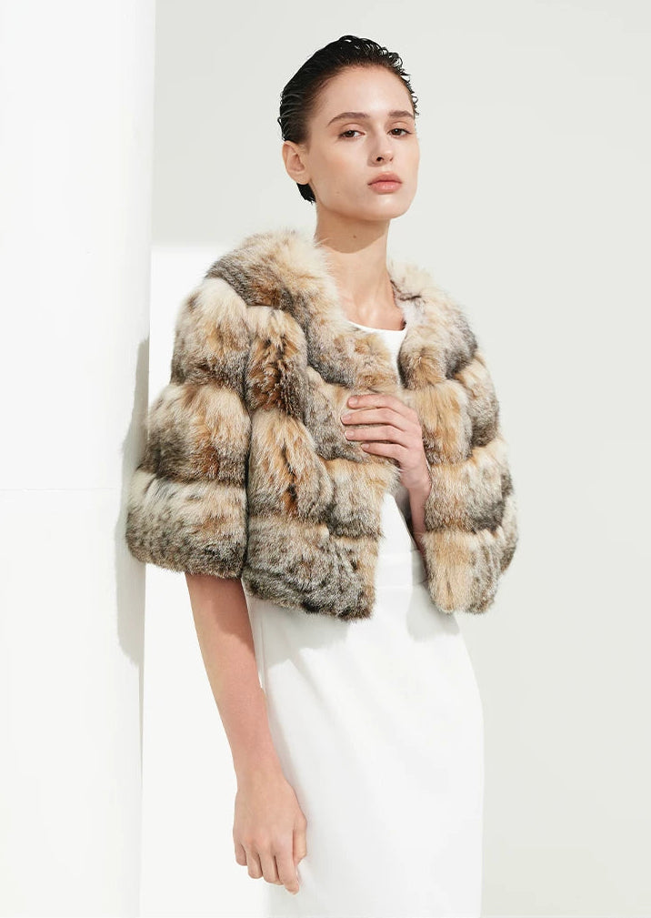 Woman gently holding the edge of her unfastened lynx cape to unveil the pure silk interior and hidden furrier clasp — From Borcelleclothes.