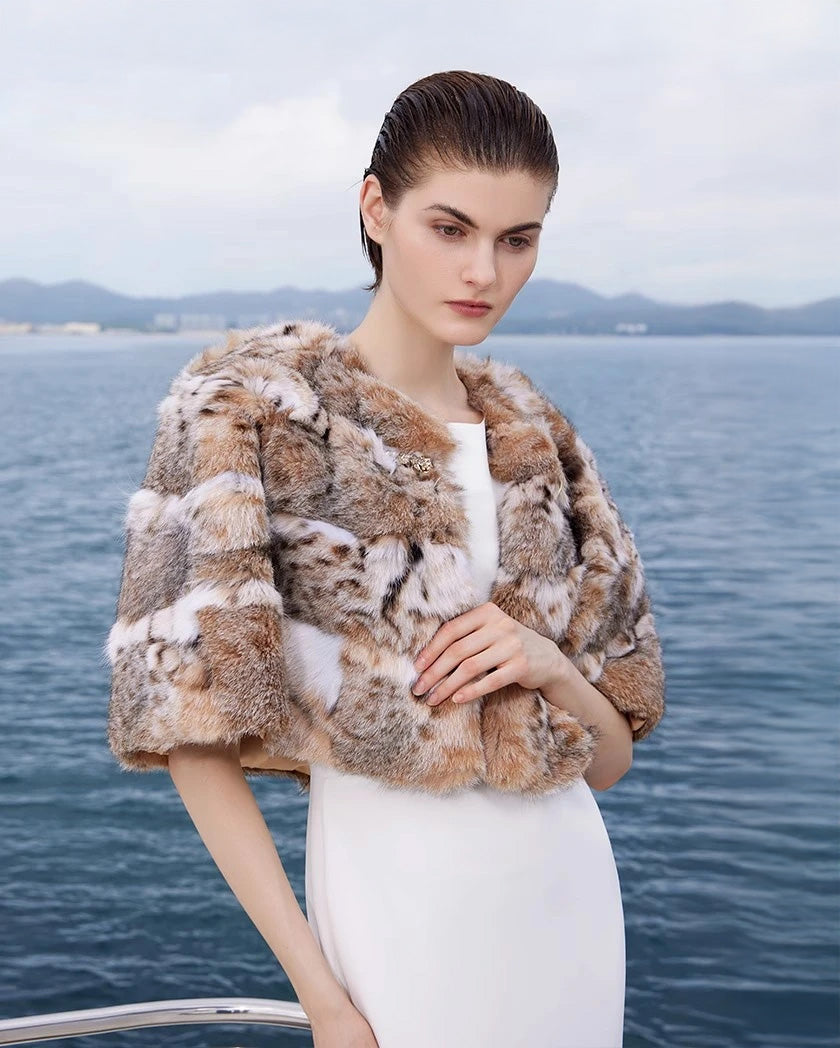 Women's Lynx fur cape in Shades of Forest — featuring a rounded cut, wild-spotted full-length pelts, and a sculpted gold-tone hook at the neckline. — From Borcelleclothes. 