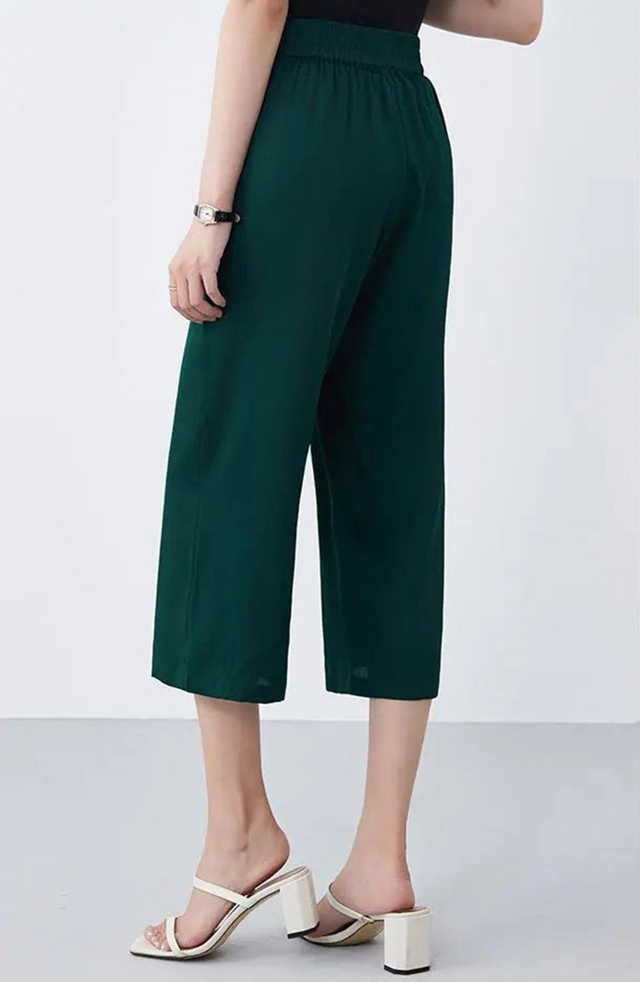 Back view of a model wearing mid-calf Mulberry silk trousers in Cyber Jade — From Borcelleclothes.