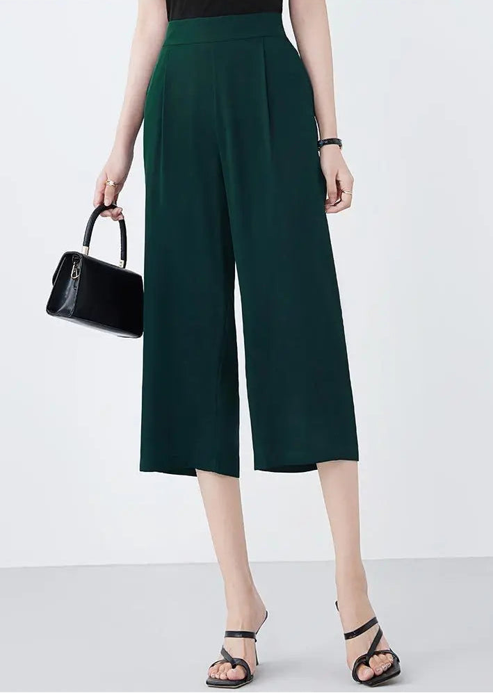 Model wearing mid-calf Cyber Jade silk trousers and holding a black handbag — From Borcelleclothes.