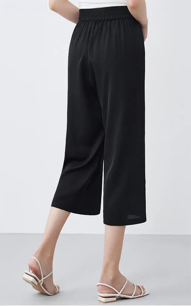 Back view of a model wearing mid-calf Mulberry silk trousers in Tactile Setting black — From Borcelleclothes.