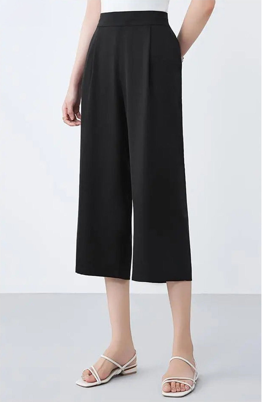 Model posing with hands behind her back in Tactile Setting black silk trousers — From Borcelleclothes.