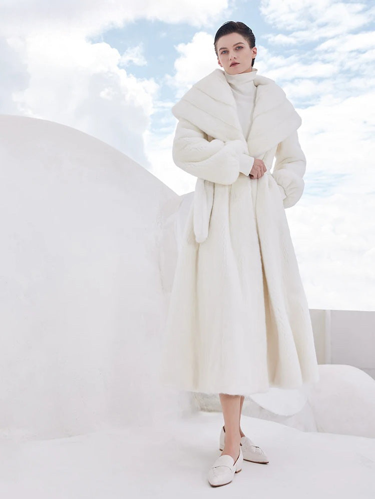 Model adjusting the belt of the white mink coat while the other hand rests in the pocket — From Borcelleclothes.