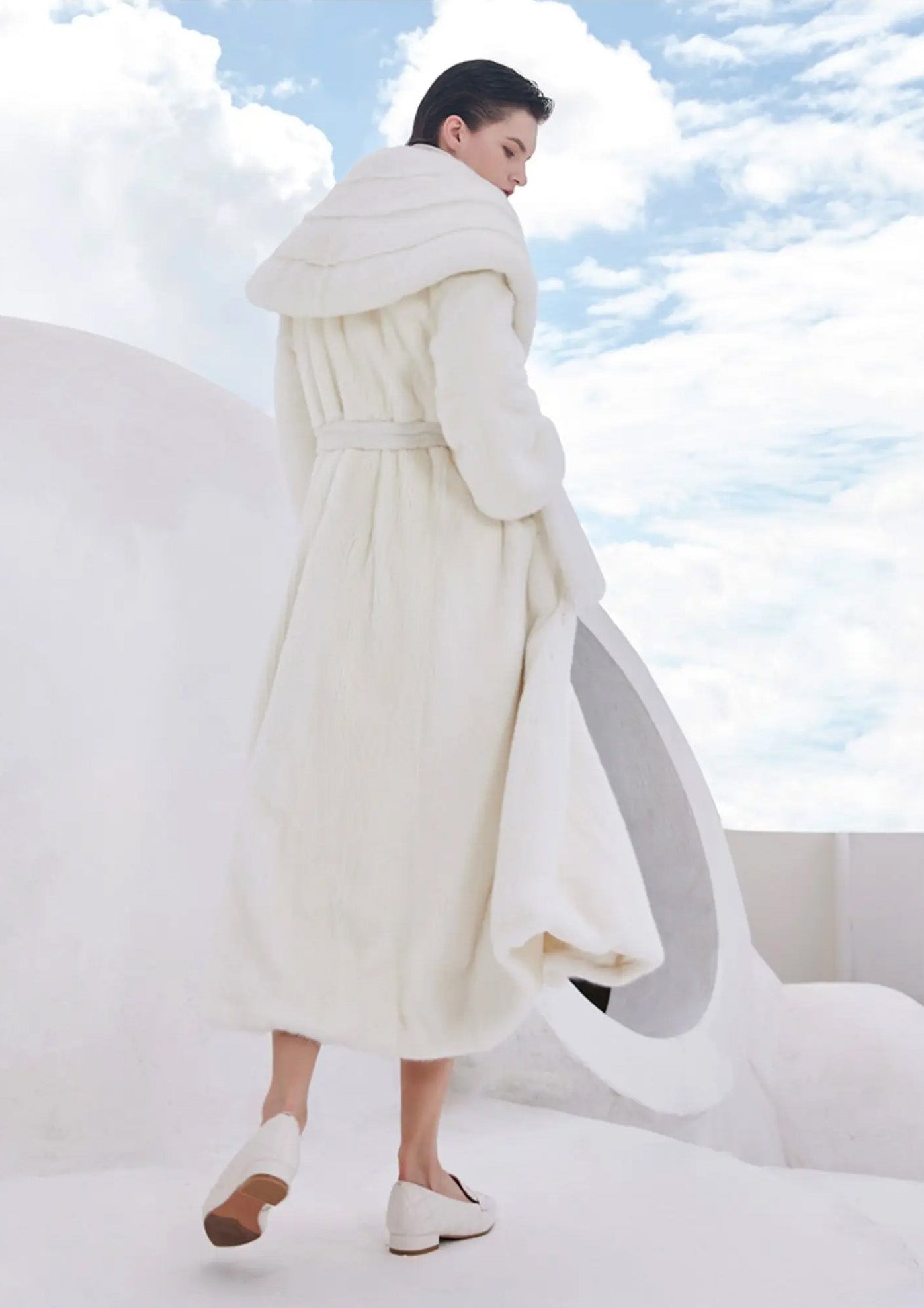 Model in motion with back view of the white mink coat, showing the fluid drape and flared hem — From Borcelleclothes.