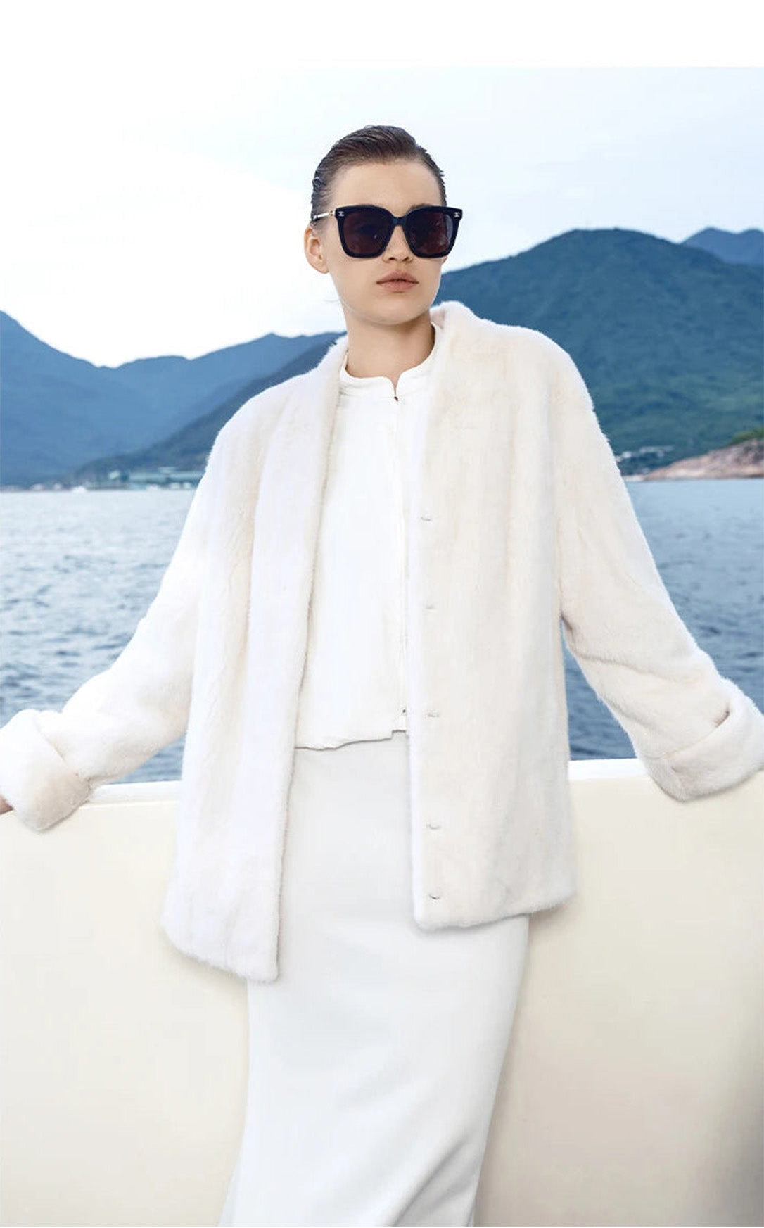 Model in Pale Reverie mink coat holding the yacht’s railing, sleeves slightly lifted — From Borcelleclothes.