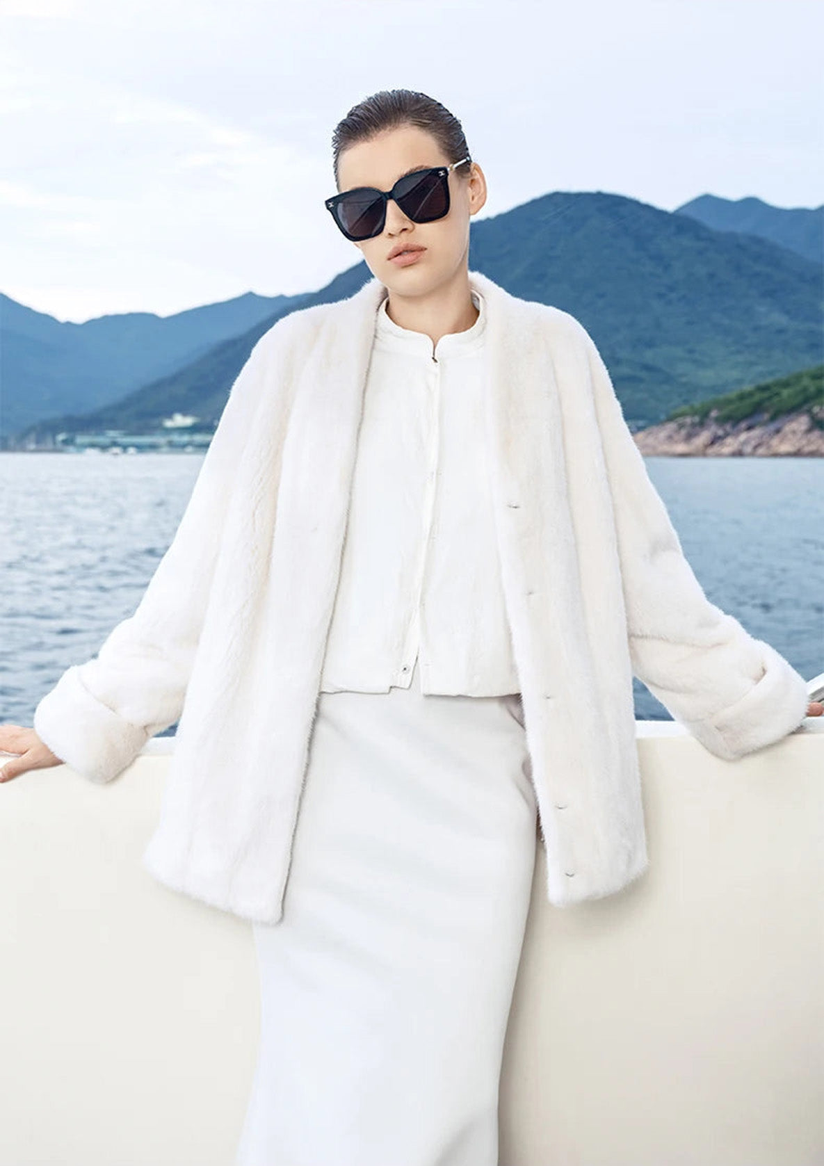Woman in Pale Reverie mink coat with V-neckline, leaning gently against the yacht’s railing — From Borcelleclothes.