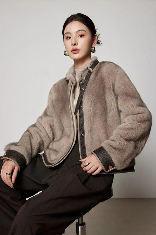 Model sitting on a chair wearing the mink fur jacket with leather neck belt in Smokey Quartz. — From Borcelleclothes.