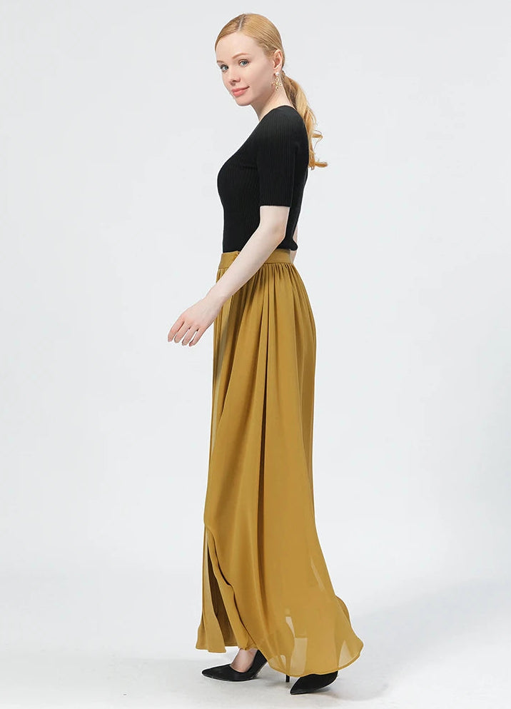 Side view of a model walking in the mid-calf silk wrap skirt, showing the unique architectural movement of the silk panels — From Borcelleclothes.