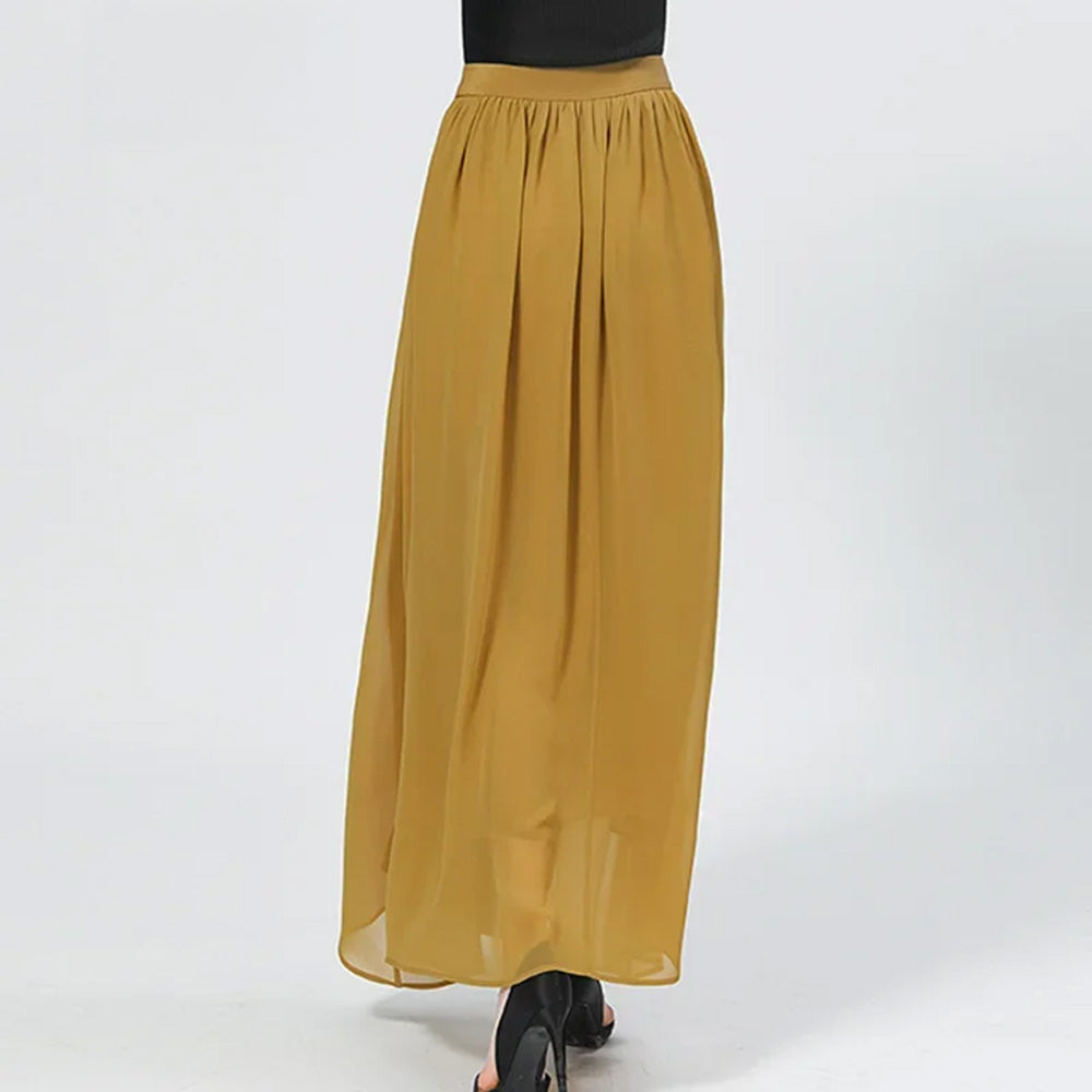 Rear view of a model walking, captured in motion to show the elegant drape of the Aztec Gold silk and georgette layers — From Borcelleclothes.