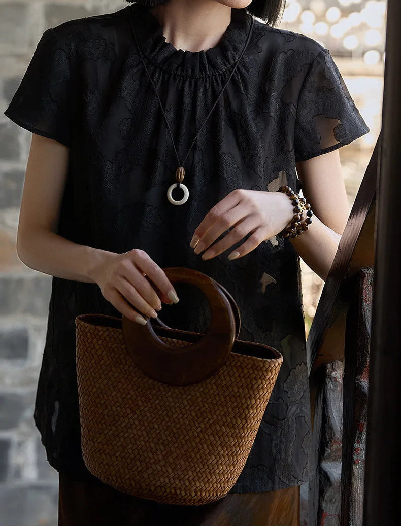 Women's Mulberry Silk Blouse in Bittersweet Noir — full look with model holding a woven summer bag, highlighting the fluid hip-length hem — From Borcelleclothes.