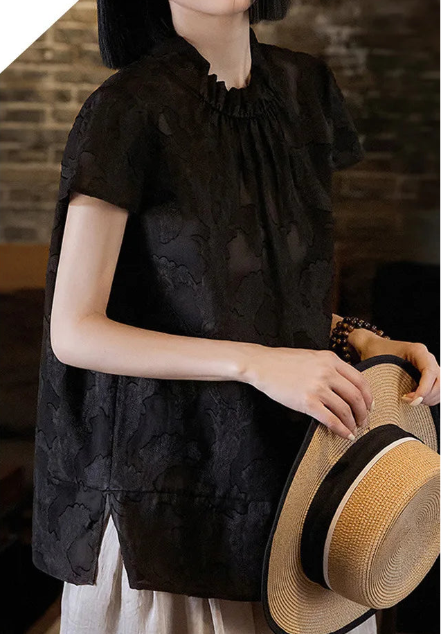 Women's Mulberry Silk Blouse in Bittersweet Noir — model standing holding a woven sun hat, styled with wide-leg trousers — From Borcelleclothes.