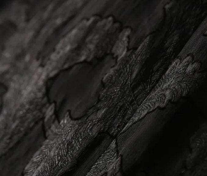 Close-up macro texture of the Mulberry Silk Blouse in Bittersweet Noir, highlighting the embossed compound jacquard leaf weave and sheer gauze base — From Borcelleclothes.
