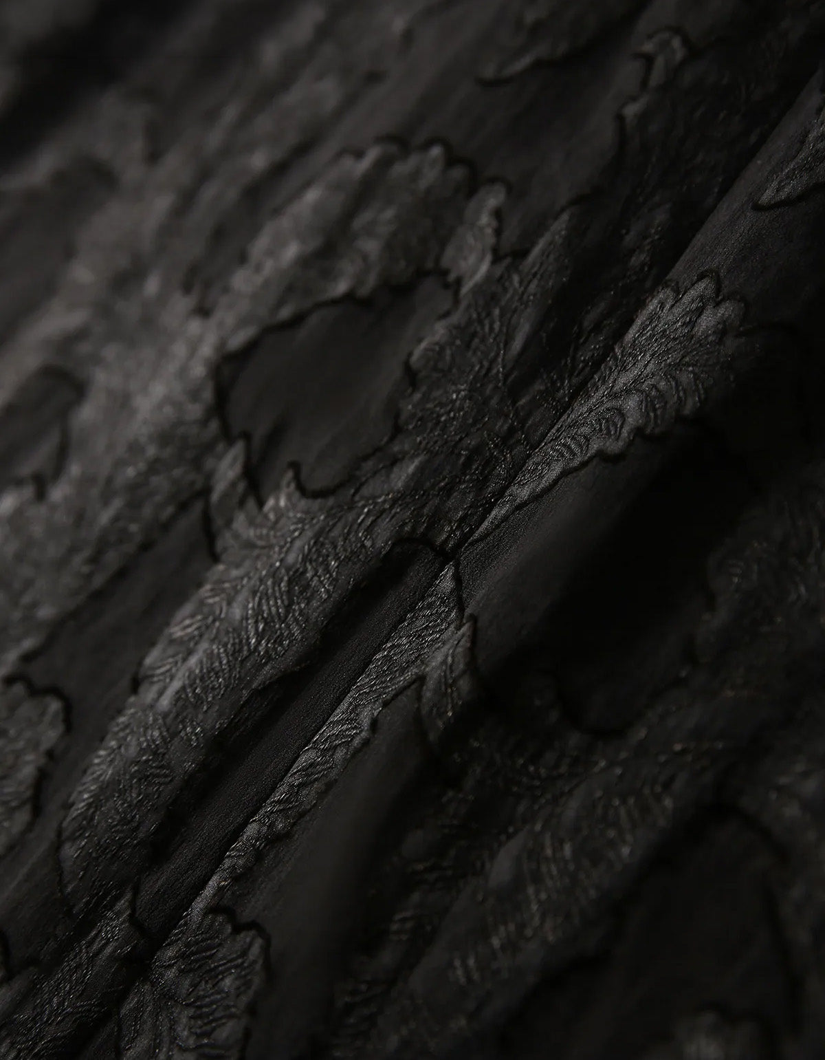Sculptural wave drape of the Xiangyunsha silk fabric in Bittersweet Noir, displaying the tactile leather-like relief on the face side — From Borcelleclothes.