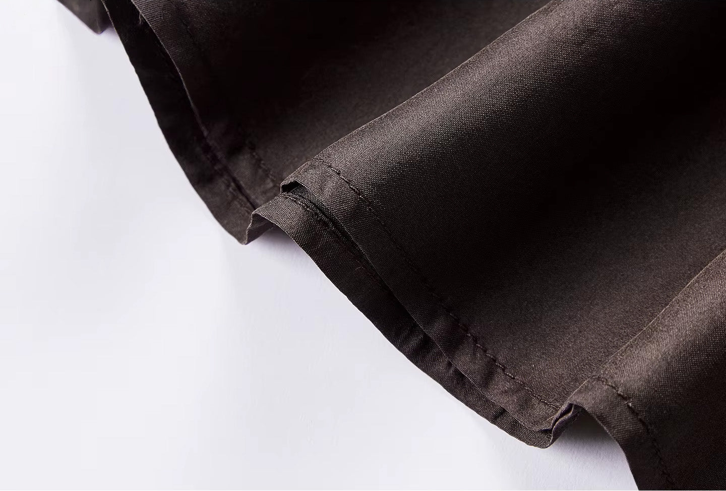 Detailed view of the topstitched bottom hem of a flared silk midi skirt — From Borcelleclothes.
