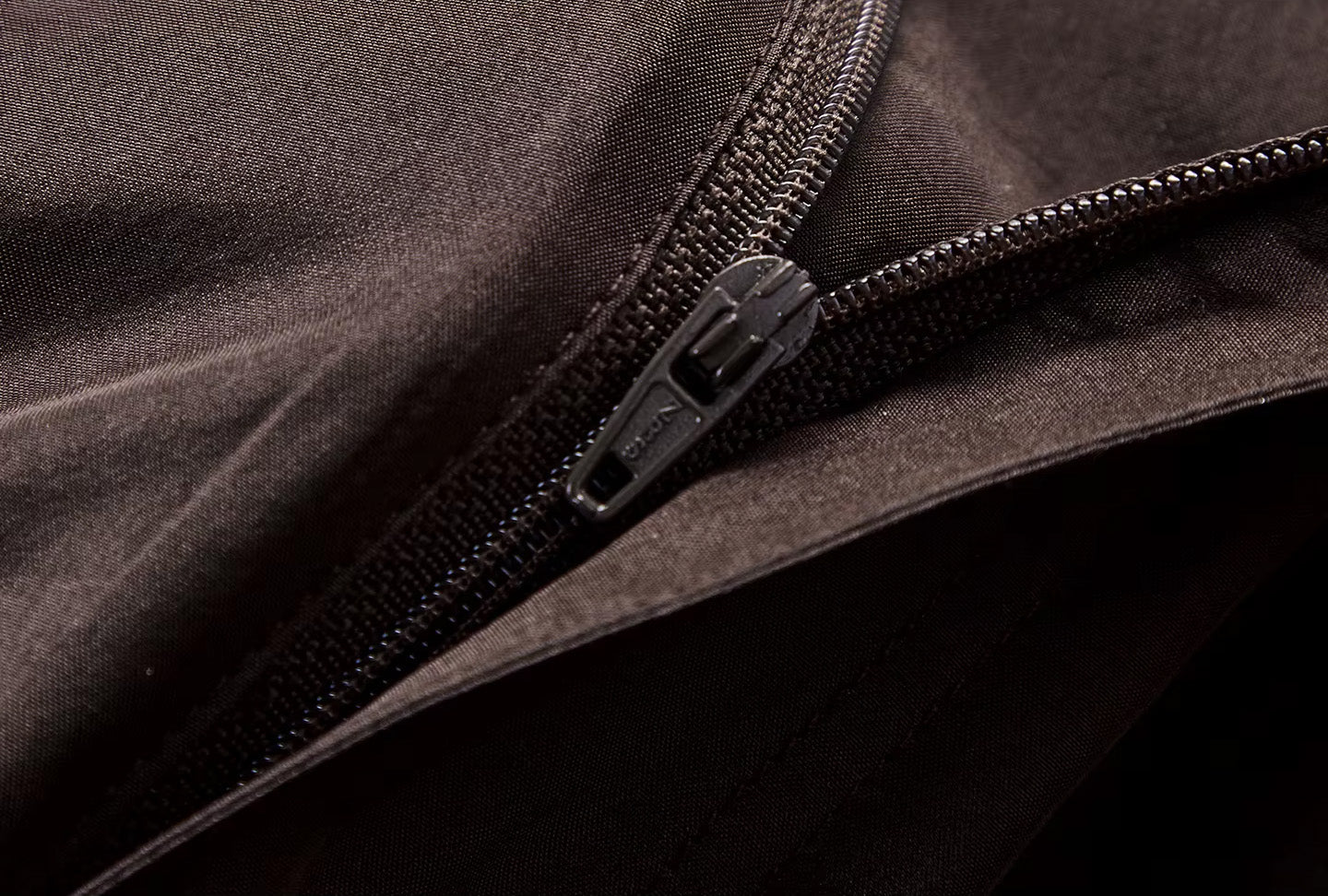Macro view of the front waistband with an unzipped structured zipper fly on a Bitter Chocolate silk skirt — From Borcelleclothes.