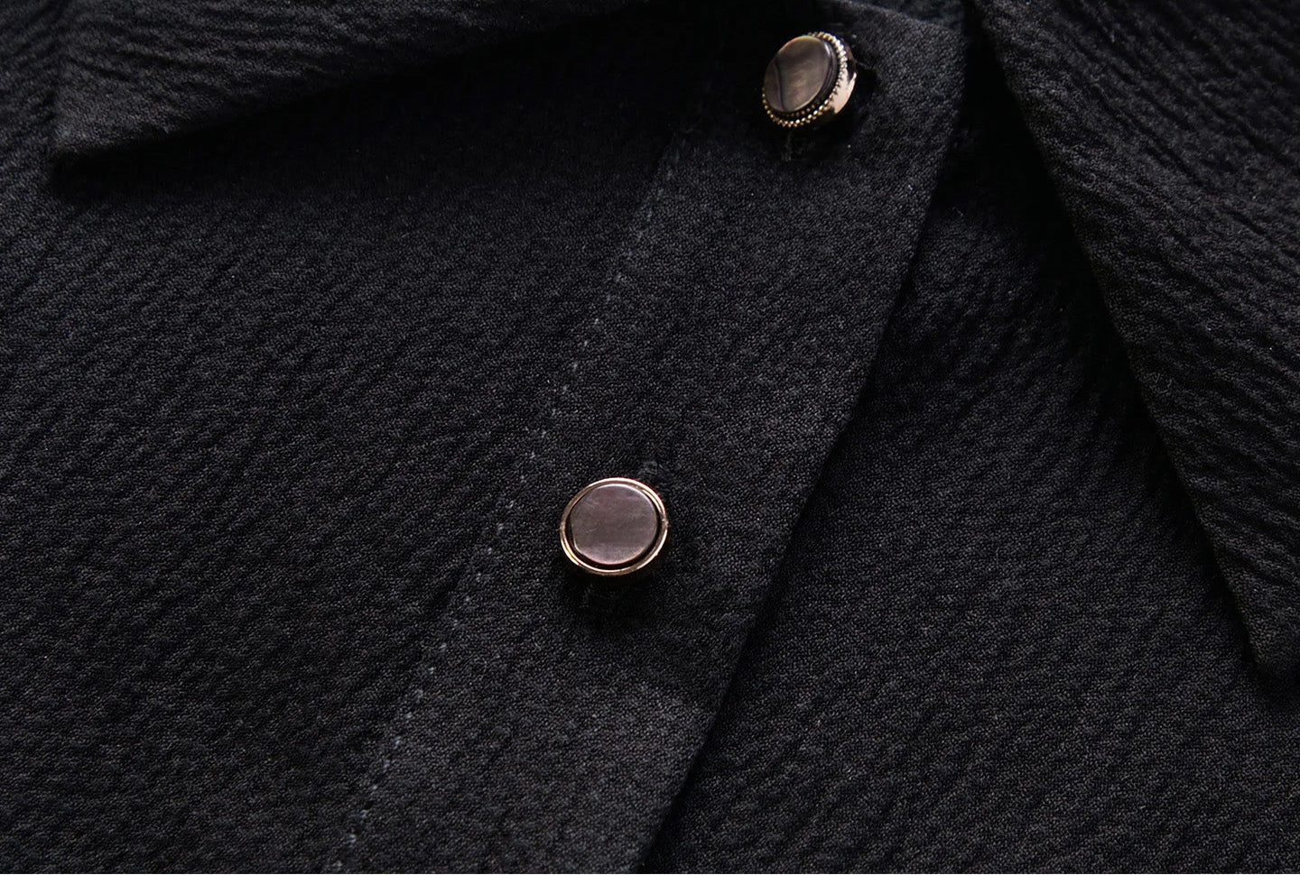 Close-up of gold-tone bezel buttons inlaid with natural black mother-of-pearl on the front placket — From Borcelleclothes.