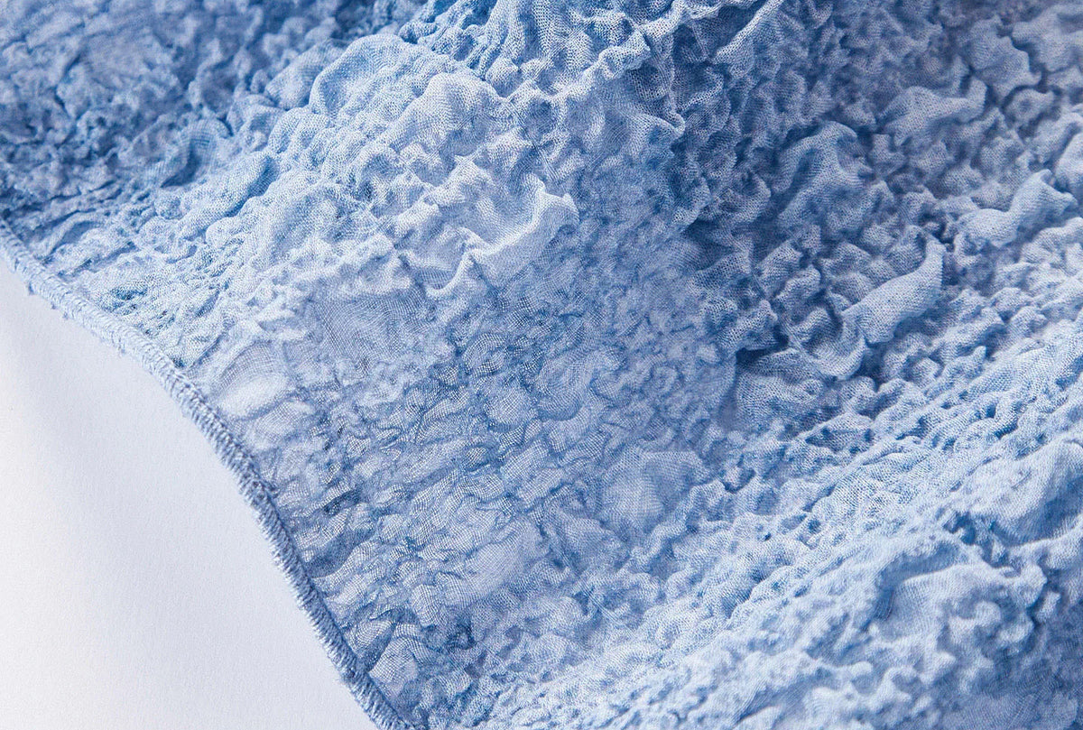Detailed close-up of the dense serged edge finish along the bottom hem of the Cloudy Sky silk top — From Borcelleclothes.