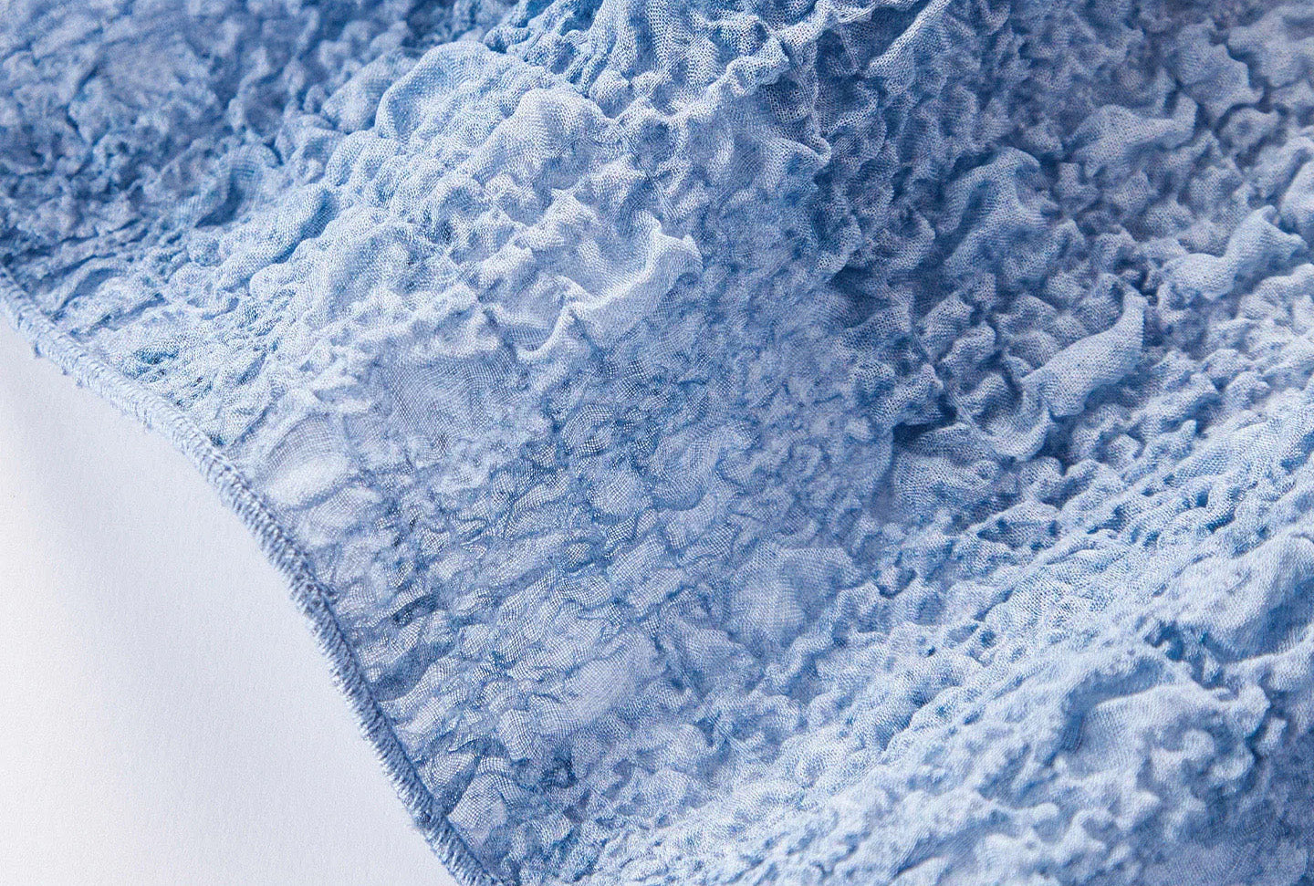 Detailed close-up of the dense serged edge finish along the bottom hem of the Cloudy Sky silk top — From Borcelleclothes.