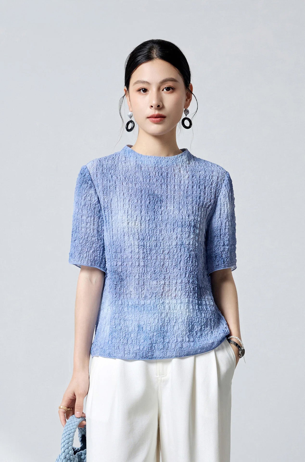Model styled with a blue woven bag wearing the Cloudy Sky mulberry silk puckered jacquard top — From Borcelleclothes.