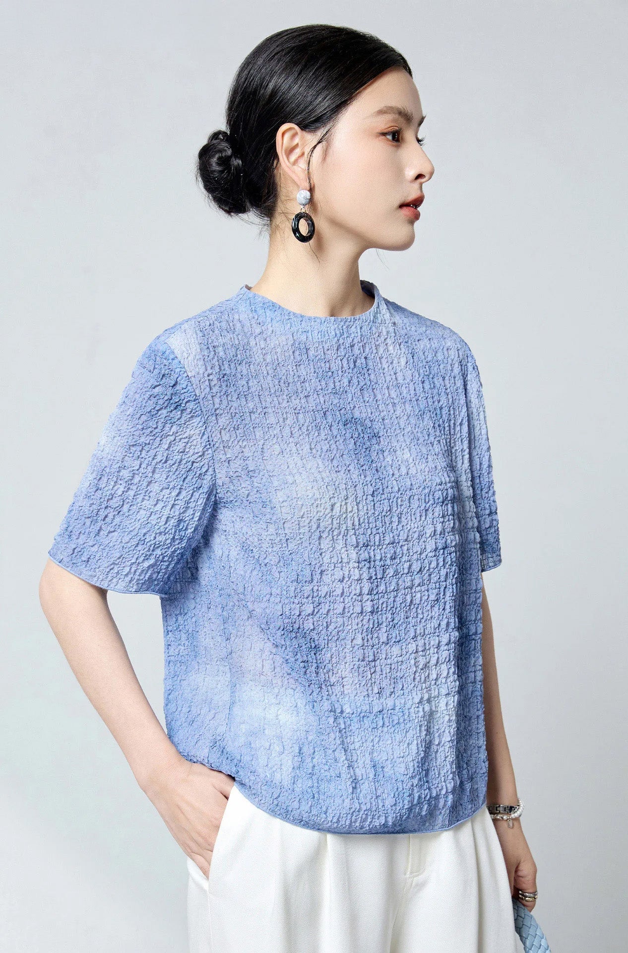 Model looking aside with hand in trouser pocket wearing the Cloudy Sky silk jacquard top — From Borcelleclothes.