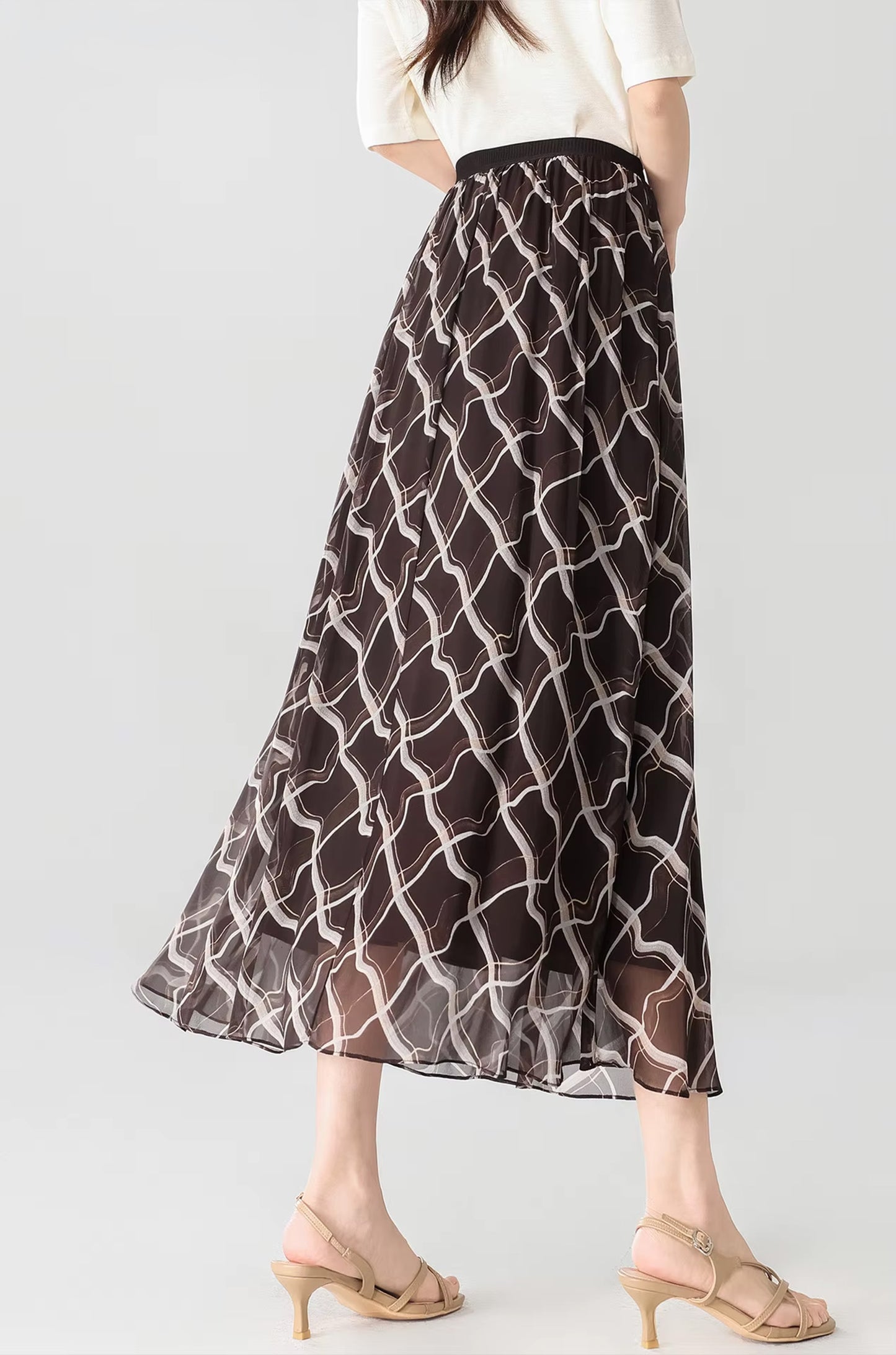 Back view of a model wearing the Café Mirage brown silk skirt with geometric pattern — From Borcelleclothes.