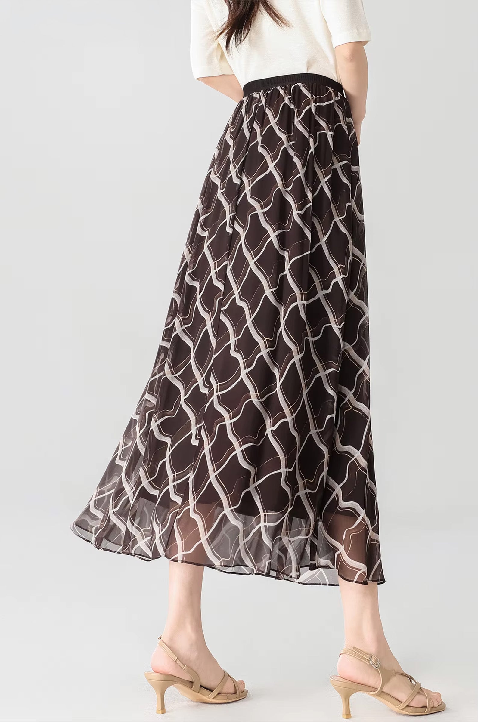 Back view of a model wearing the Café Mirage brown silk skirt with geometric pattern — From Borcelleclothes.