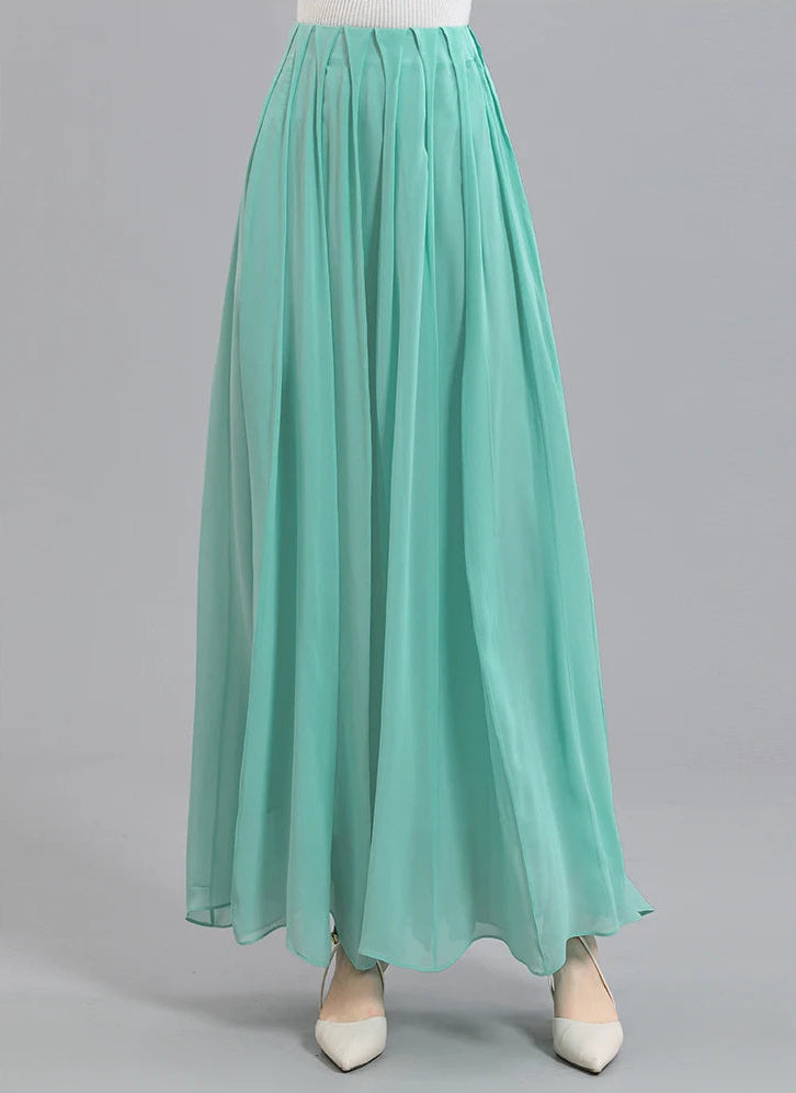 Front view of a model wearing a women's Mulberry silk skirt with spread pleats in Cross Waves, with her foot stepped aside — From Borcelleclothes.