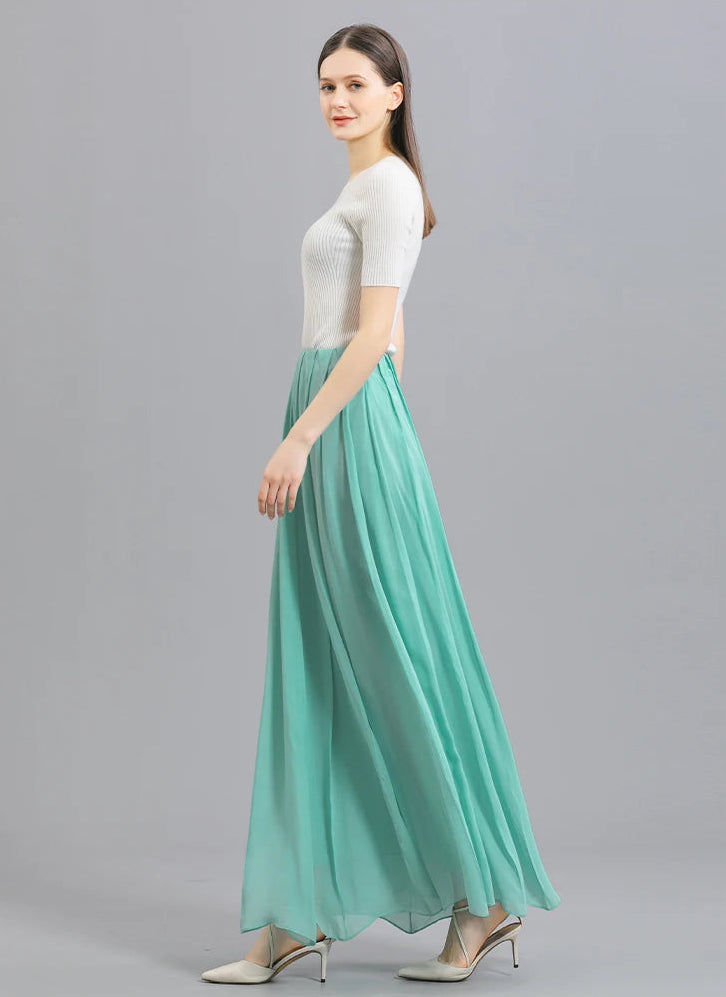 Full-height side view of a model walking in a women's Mulberry silk skirt with spread pleats in Cross Waves — From Borcelleclothes.