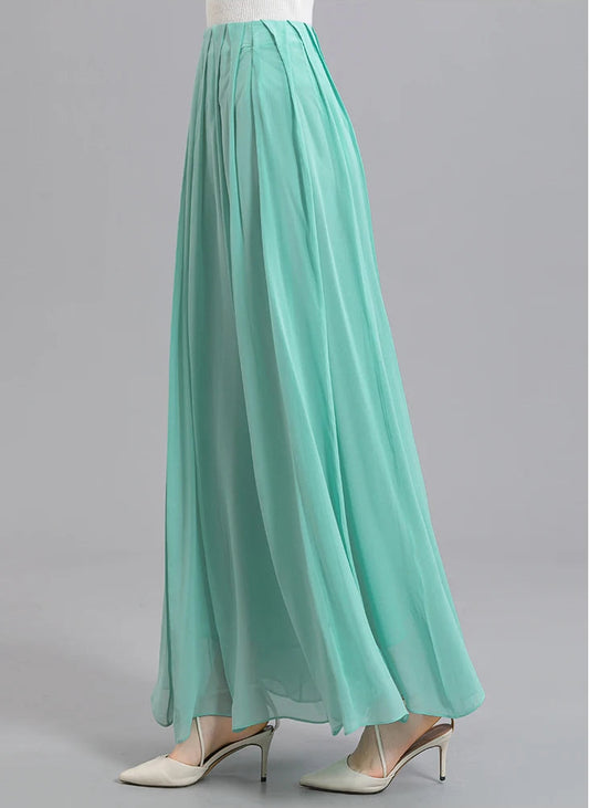 Side view of a model walking in a women's Mulberry silk skirt with spread pleats in Cross Waves — From Borcelleclothes.