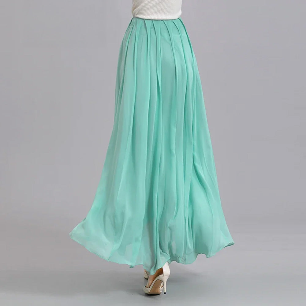 Back view of a model walking in a women's Mulberry silk skirt with spread pleats in Cross Waves — From Borcelleclothes.