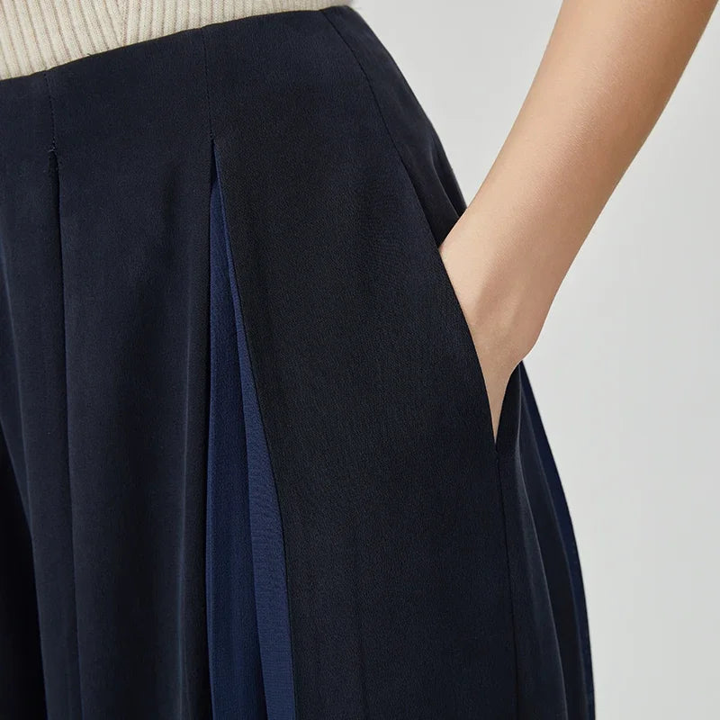 Close-up of a woman's hand in the side pocket of Mulberry silk trousers with georgette inserts in Vortex Flower — From Borcelleclothes.