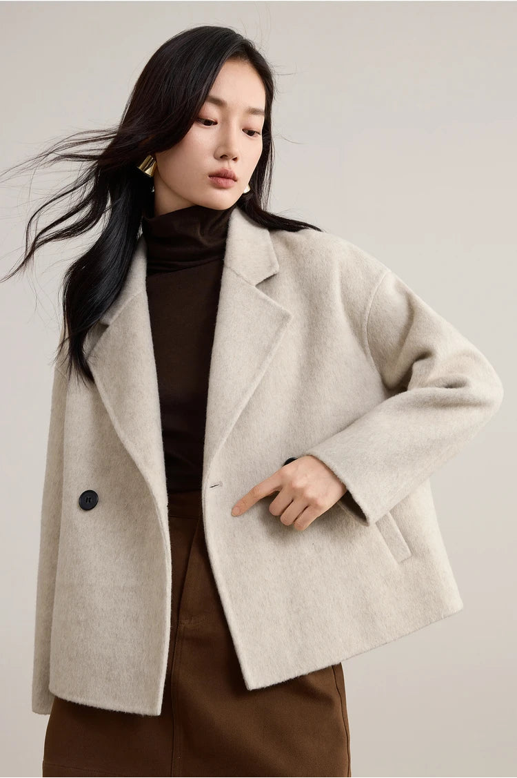 A woman posing in an unfastened Bohemian light wool jacket with a bent arm, highlighting the relaxed double-breasted silhouette. — From Borcelleclothes.