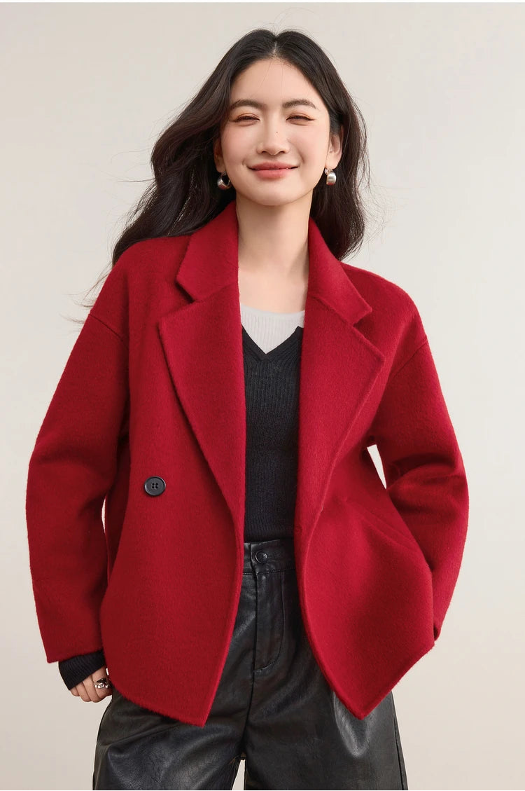 A confident woman in a Sweet Rebellion red wool jacket with hands on her hips, showcasing the bold, unfastened front. — From Borcelleclothes.