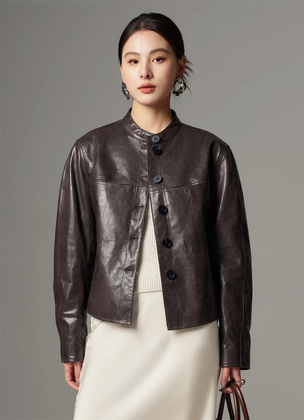 Editorial shot of model carrying a leather bag paired with the First Impression goatskin overshirt jacket — From Borcelleclothes.