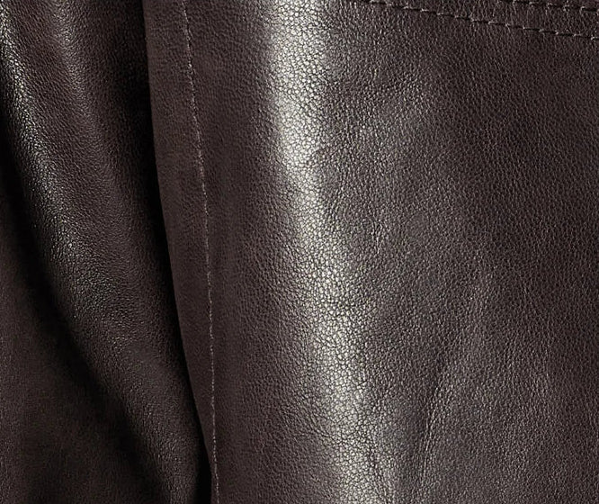 Macro texture detail of full-grain oil-waxed goatskin showing dynamic pull-up undertones and fine natural pebble grain — From Borcelleclothes.