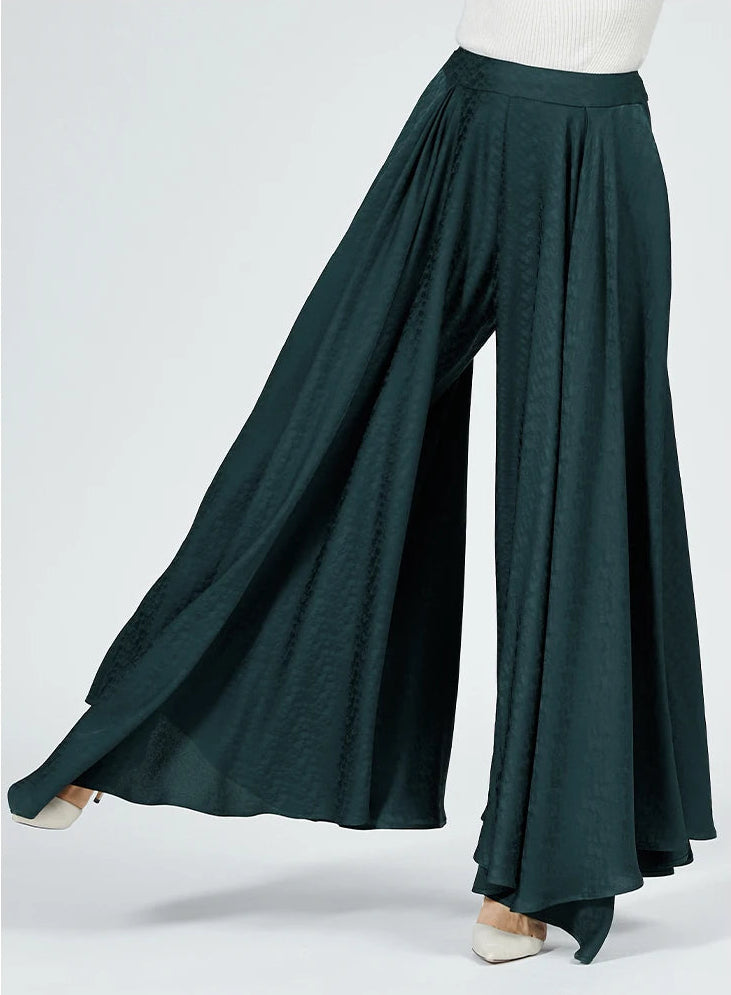 A side view of a woman with her leg slightly lifted, demonstrating the wide-leg silhouette, the elegant drape, and the unique silk jacquard texture. — From Borcelleclothes.