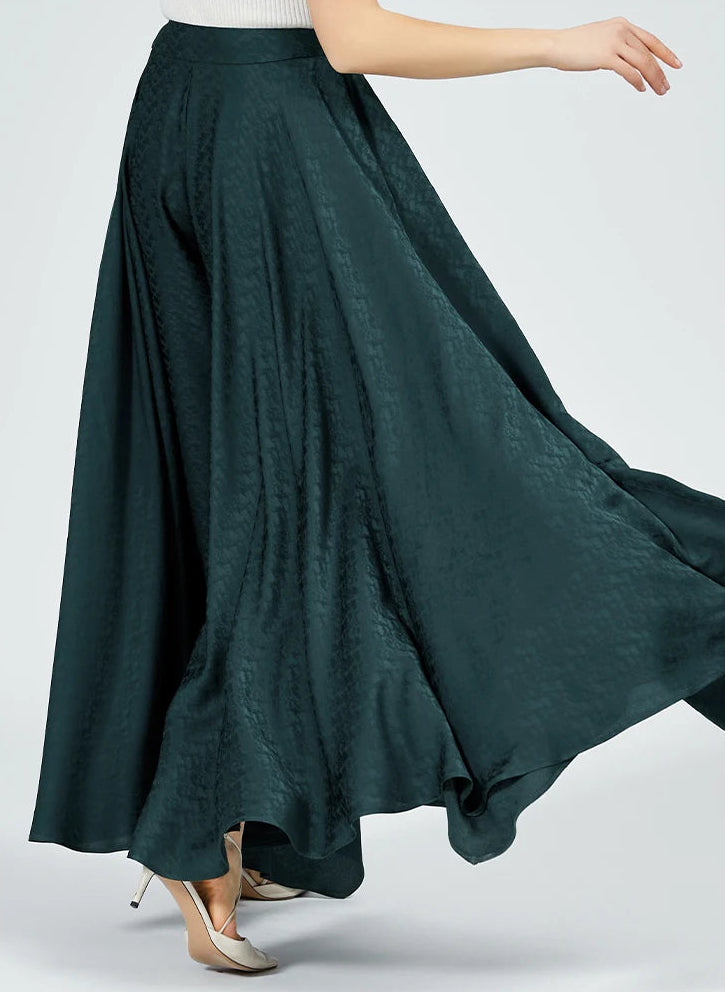 Back view of a woman in motion, showing how the rich emerald silk fabric billows and swirls around her, capturing the light. — From Borcelleclothes.