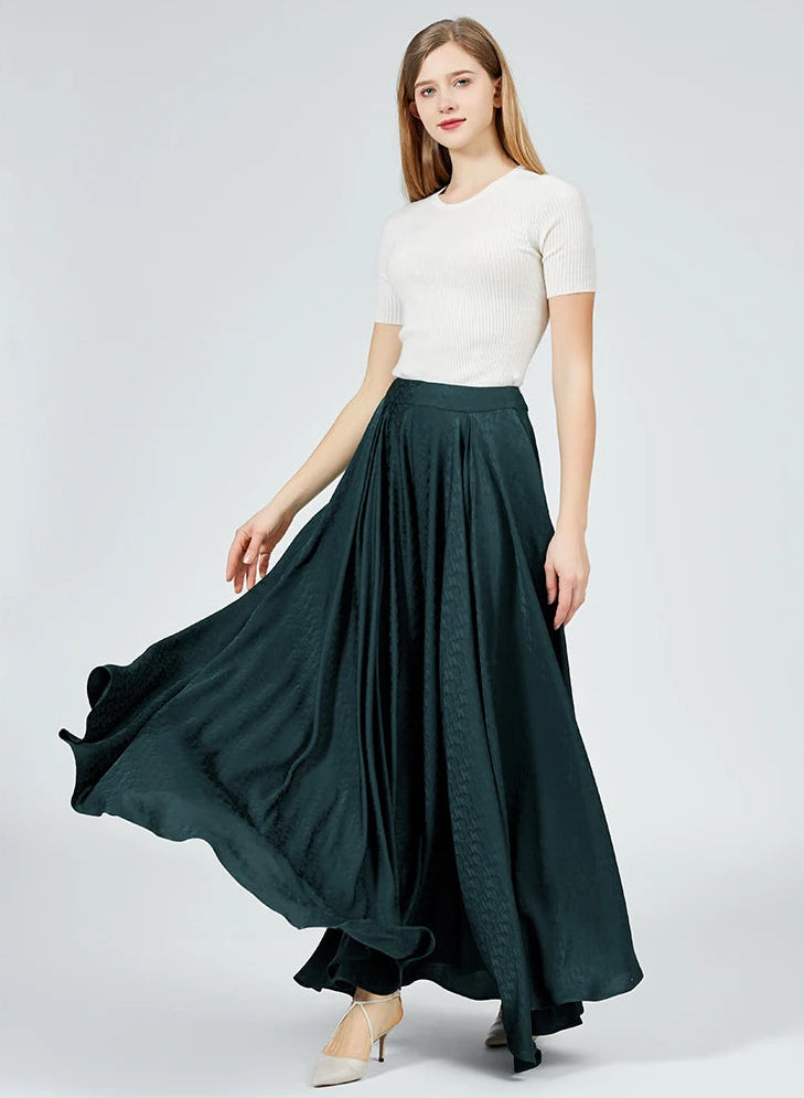 Front view of a woman swirling, transforming the voluminous silk jacquard trousers into a beautiful vortex of cascading emerald waves. — From Borcelleclothes.